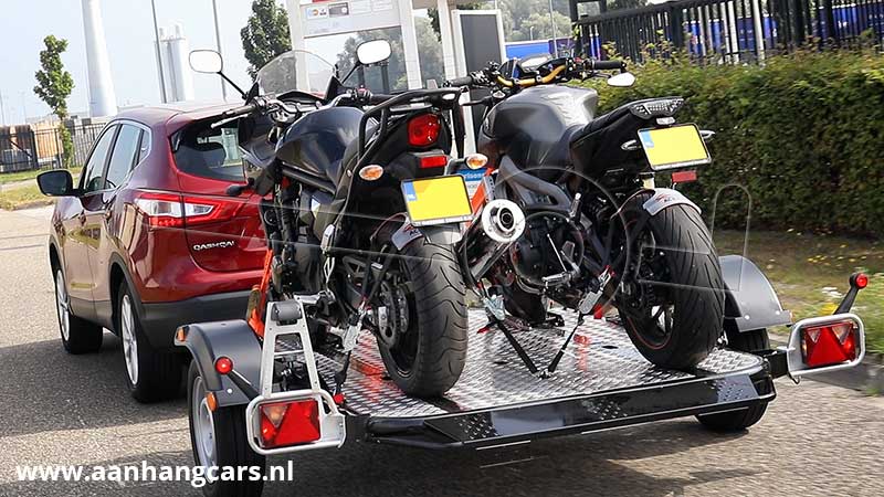 Auto met daarachter een Cochet Duo zak- en opvouwbare motortrailer waar twee motoren op staan