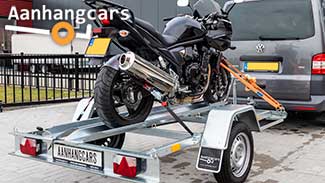 Motor vastgesjord op enkelas motortrailer achter bestelbus