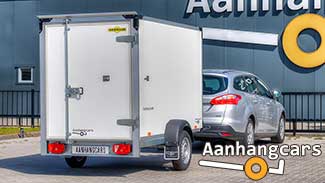 Ongeremde enkelasser Humbaur gesloten aanhangwagen achter een zilverkleurige auto