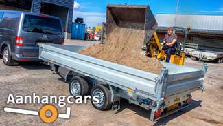 Kleine graafmachine dumpt zand in de laadbak van een Humbaur HTK driezijdige kipper