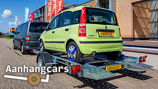 Rijdende bestelbus met daarachter een Martz enkelas kantelbare autotransporter waar een kleine groende stadsauto staat