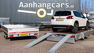 Plateauwagen naast een multitransporter waar een auto op staat