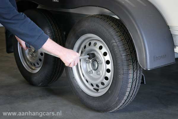 Monteur trekt wielbouten van aanhangwagen aan